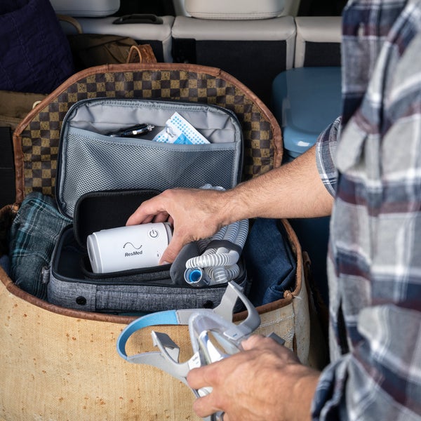ResMed AirMini travel CPAP device being placed into travel bag