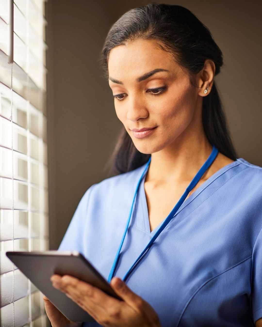 Nurse in blue scrubs using a tablet computer