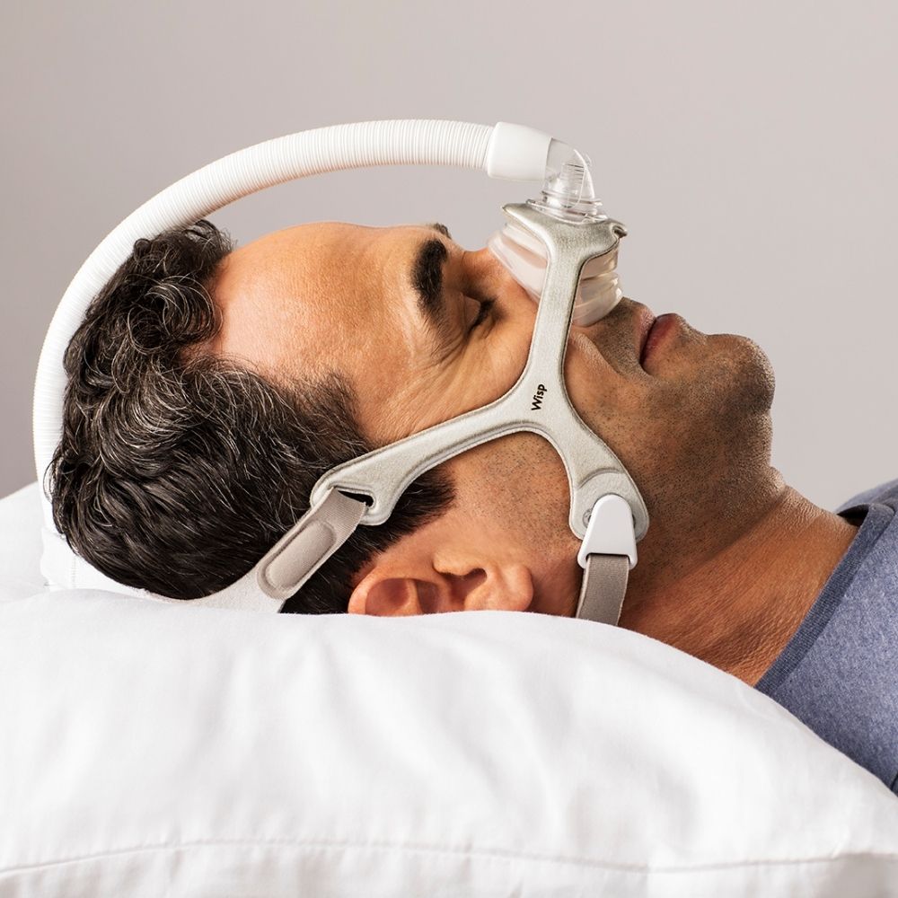 Person sleeping while using Philips Wisp Nasal Mask with Fabric Frame and tube