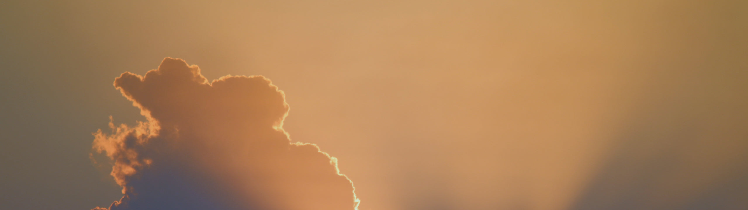 Silhouette of a cloud against a warm, gradient sky