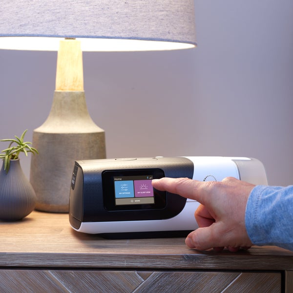 ResMed AirSense 11 AutoSet CPAP machine powered on top of nightstand