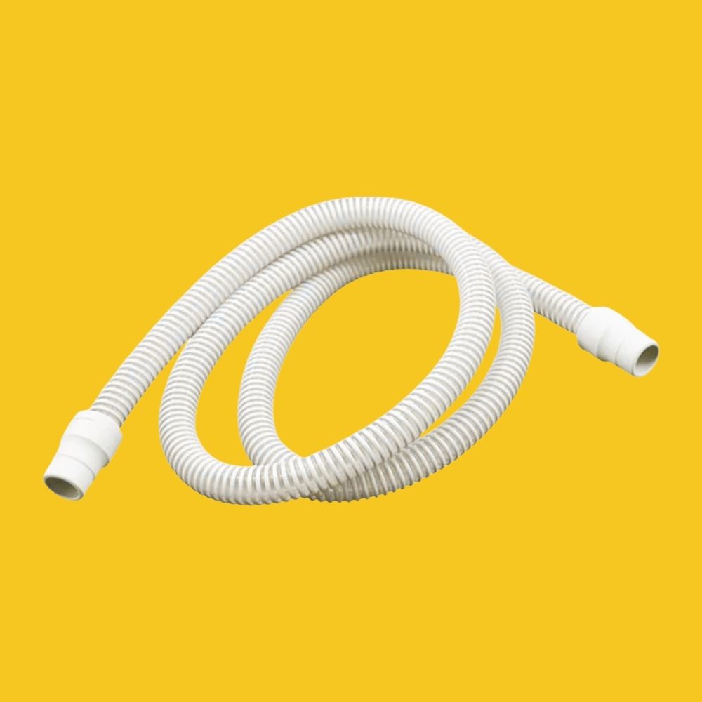 White flexible CPAP hose on a yellow background