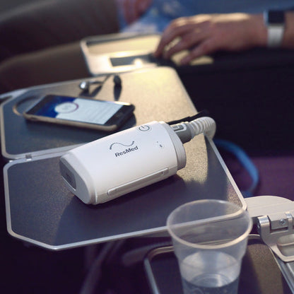 ResMed AirMini travel CPAP device on airplane table tray