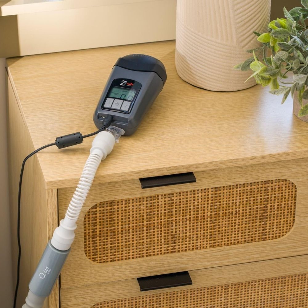 Breas Z2 CPAP device on wooden nightstand connected to tube and power