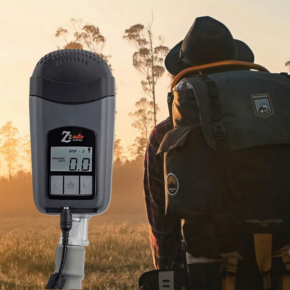 Person with a backpack and Z2 Auto travel CPAP machine shown in a field during sunset