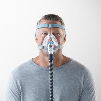 A person wearing the F&P Vitera Full Face CPAP Mask with a tube
