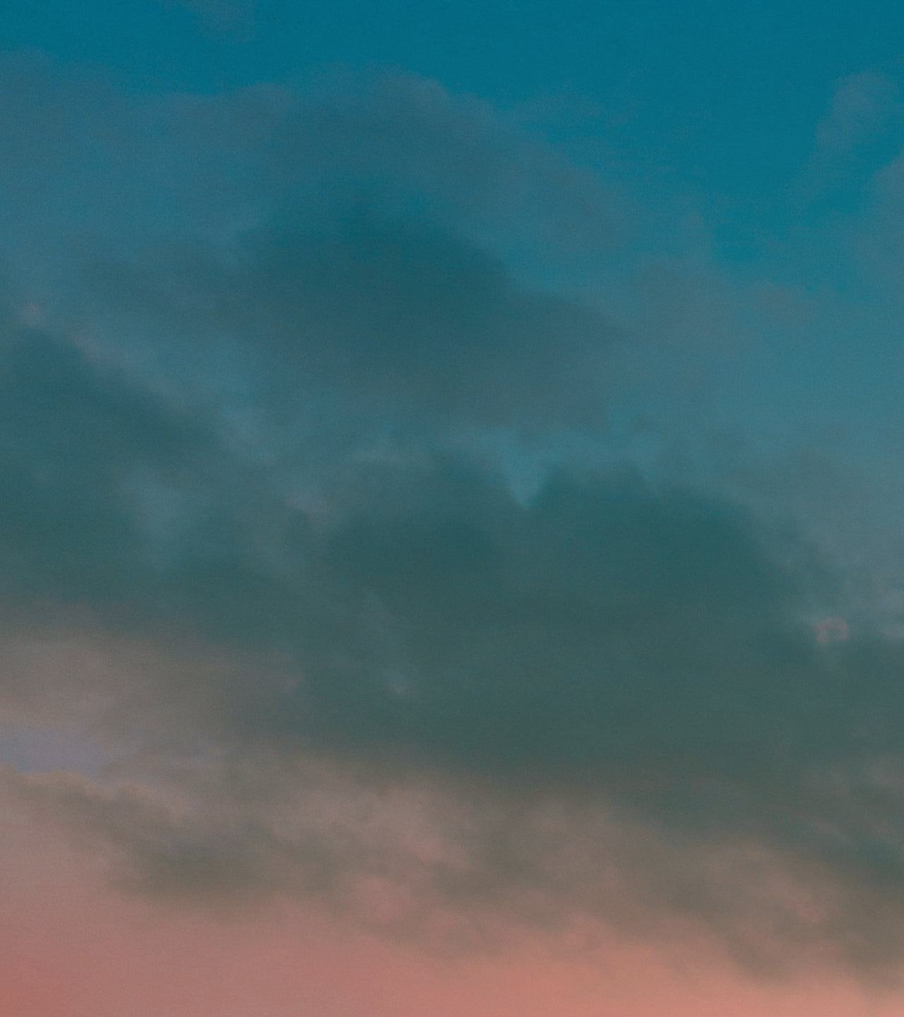 Calm sky with clouds against a dark blue gradient transitioning to soft pink sunset