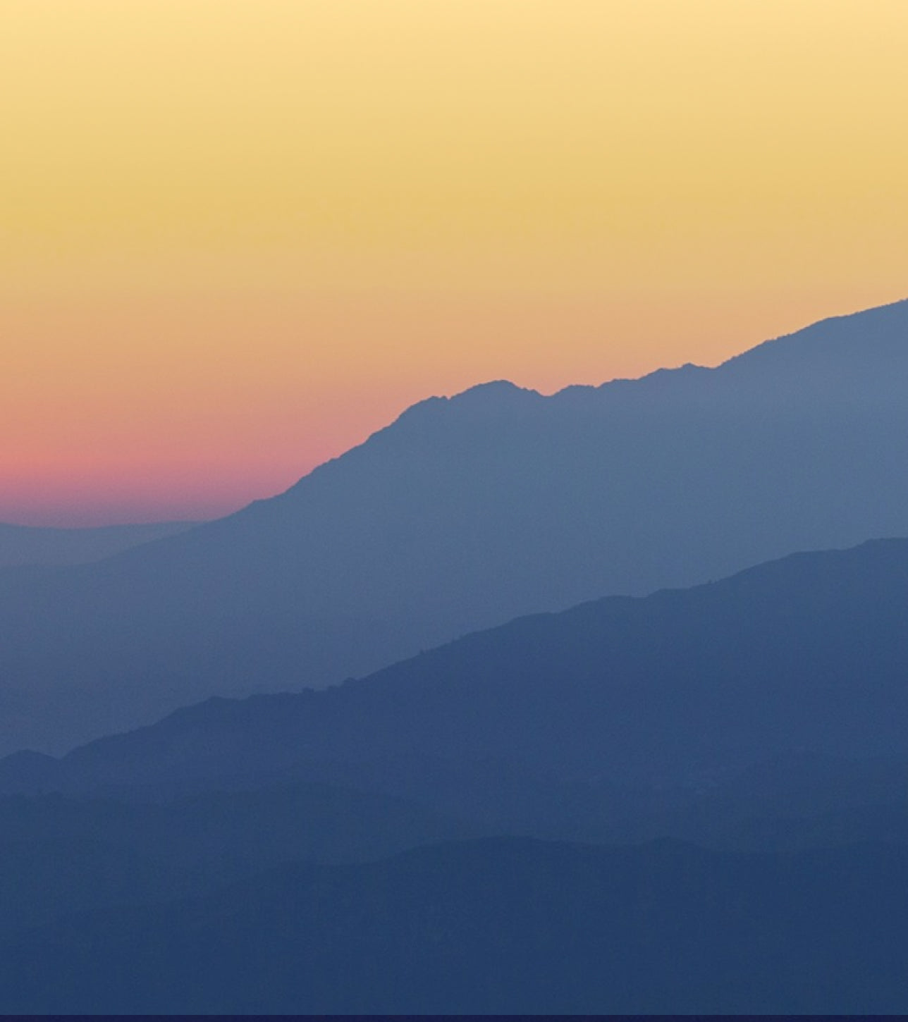 Silhouette of mountains against a colorful sky with pink and orange hues
