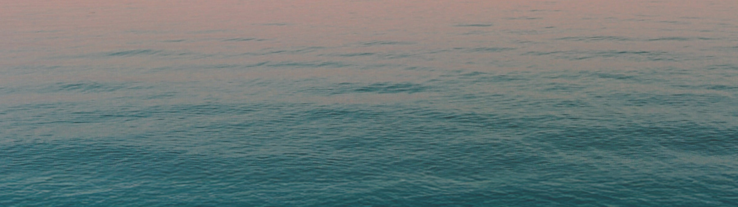 Calm ocean surface with a gradient of blue and pink hues