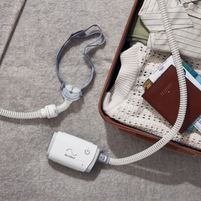 ResMed AirFit P10 for AirMini beside suitcase and AirMini CPAP device