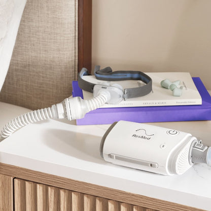 ResMed AirFit P10 for AirMini mask with connector and tube on nightstand beside AirMini CPAP device