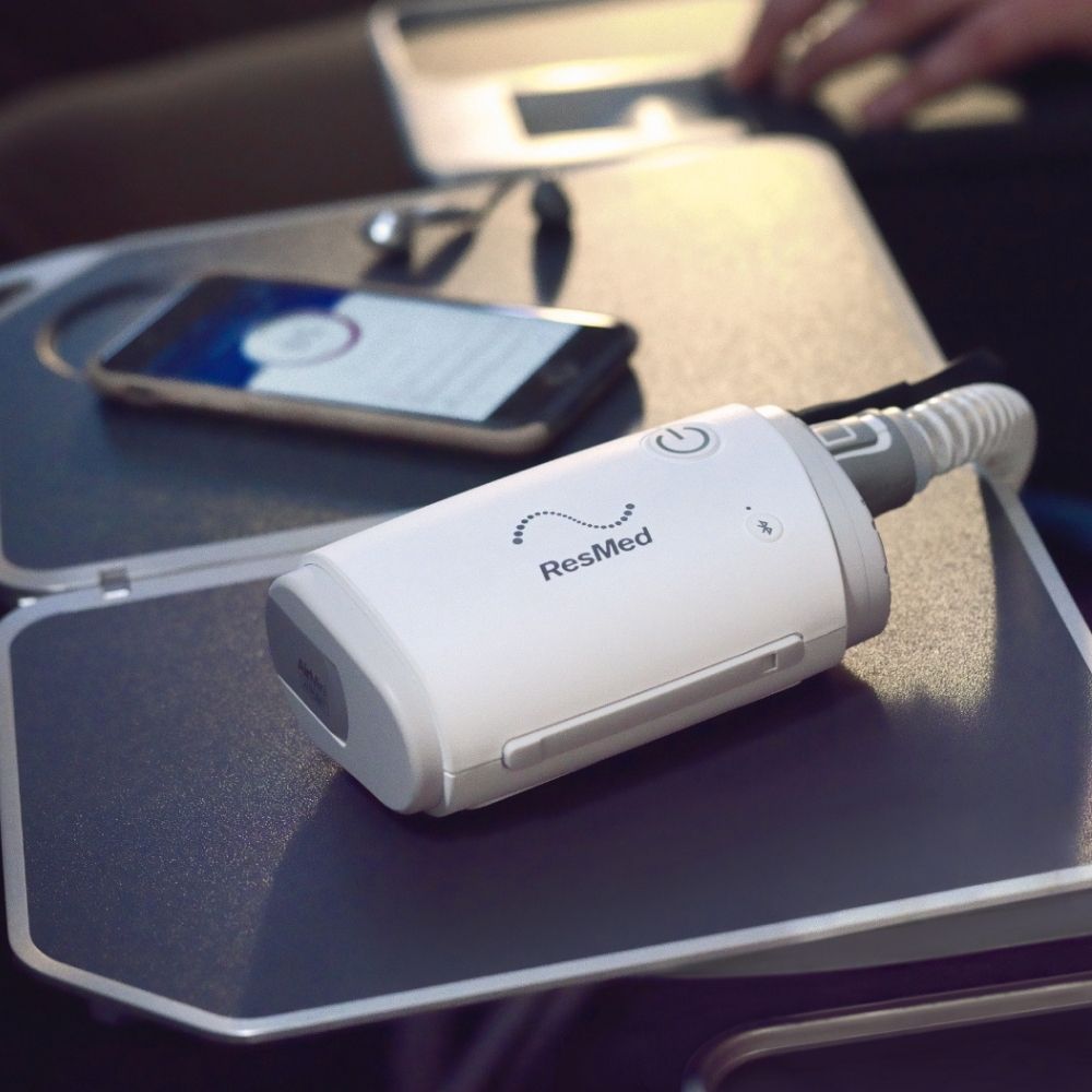 ResMed AirMini on an airplane tray with a smartphone in the background