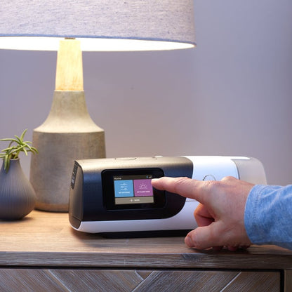 ResMed AirSense 11 AutoSet CPAP machine powered on top of nightstand