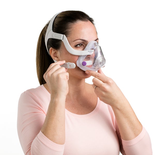 Woman removing the clip on the ResMed AirTouch N20 for Her Nasal CPAP Mask